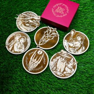 Porta-copos inspirados em O Senhor dos Anéis, feitos com madeira de reflorestamento e gravados a laser, apresentando personagens como Smaug, Arwen, Samwise, Sauron e Radagast, com detalhes incríveis e acabamento envernizado. | Coasters inspired by The Lord of the Rings, made with reforested wood and laser engraved, featuring characters like Smaug, Arwen, Samwise, Sauron, and Radagast, with amazing details and a varnished finish.