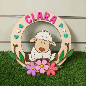 Guirlanda personalizada de ovelhinha com flores, feita com madeira de reflorestamento sustentável, cortada e gravada a laser, pintada à mão com tinta acrílica e com fita dupla face para pendurar | Personalized sheep garland with flowers, made from sustainable reforestation wood, laser-cut, hand-painted with acrylic paint, and includes double-sided foam tape for hanging.