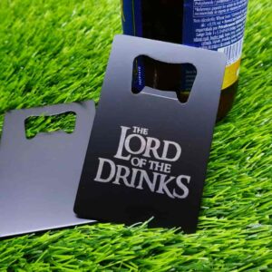 Abridor de garrafas em aço inoxidável preto com design gravado a laser inspirado em "O Senhor dos Anéis", com a frase engraçada "O Senhor das Bebidas" — perfeito para fãs de fantasia e cerveja. | Black stainless steel bottle opener with laser-engraved design inspired by "The Lord of the Rings," humorously reading "The Lord of the Drinks" — perfect for fantasy and beer lovers.
