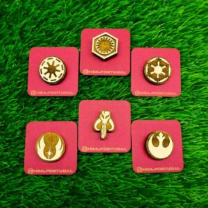 Pins de madeira com símbolos icônicos do universo Star Wars, como Mandalorian, Rebel Alliance e Jedi Order, em madeira gravada e pintada, sobre fundo neutro | Wooden pins with iconic Star Wars symbols like Mandalorian, Rebel Alliance, and Jedi Order, engraved and hand-painted, on a neutral background