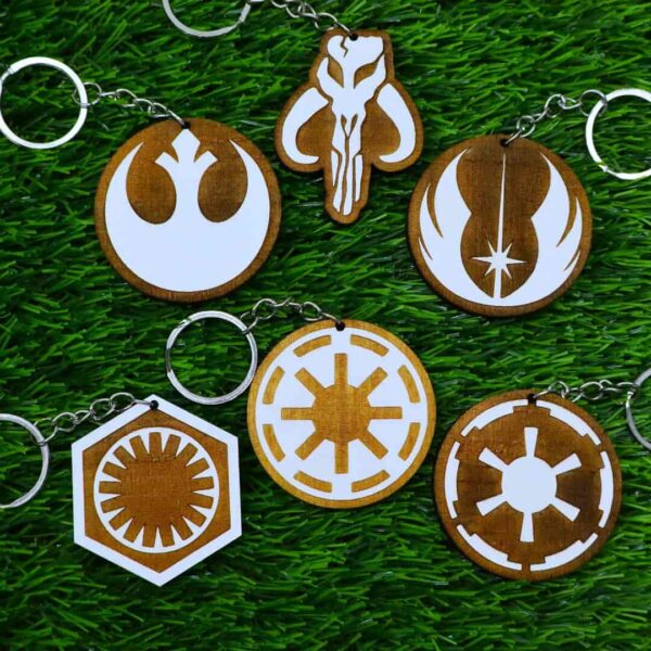 Kit de chaveiros de madeira pintados com os símbolos de Star Wars: Mandalorian, Aliança Rebelde, Império, Jedi, República e Primeira Ordem. Painted wooden keychain set featuring iconic Star Wars logos: Mandalorian, Rebel Alliance, Empire, Jedi Order, Galactic Republic, and First Order.